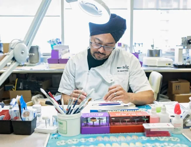 A dentist examining dental tools at a workbench.