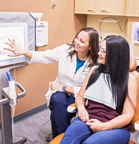 A dentist and patient discussing a dental image in a clinic.