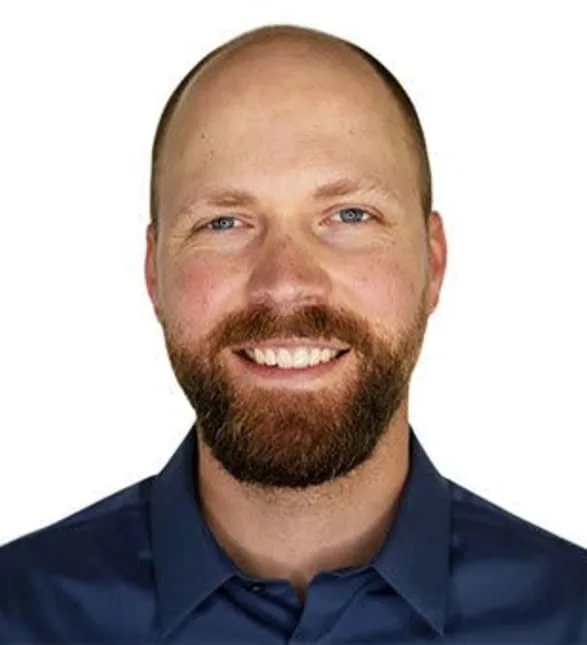 A smiling man in a blue shirt on a white background.