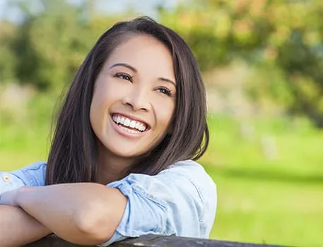 A smiling woman with long dark hair and a denim shirt.