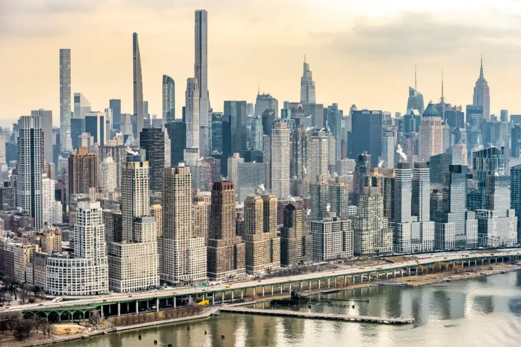 A city skyline with skyscrapers and a river in the foreground.