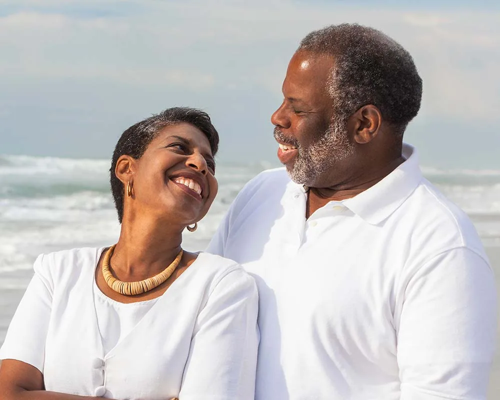 A couple smiling at each other on the beach.