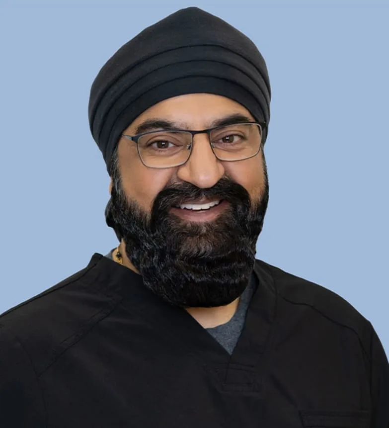 A smiling male dentist in scrubs and a turban.