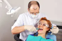 A dentist working on a patient in a dental chair.