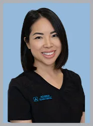 A smiling female dentist in a black uniform.