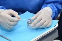 A dental professional preparing a cotton swab in a clinic.