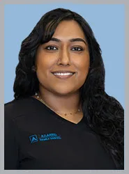 A smiling woman in dental scrubs against a blue background.