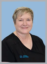 A woman in a black dental uniform smiling.