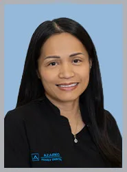 A smiling woman in a dental uniform against a blue background.