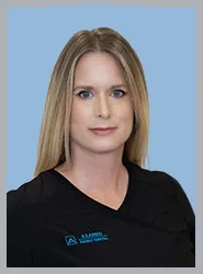 A woman in a black dental scrub top with blond hair.