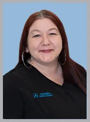 A friendly dental clinic staff member smiling in uniform.