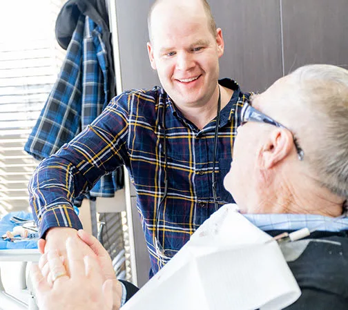 A dentist and an elderly patient in a dental office setting.