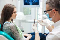 A dentist explaining a tool to a patient in a dental office.