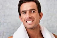 A man smiling with a towel around his neck.