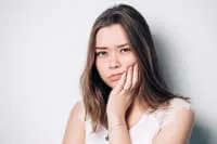 Young woman resting her chin on her hand, looking contemplative.