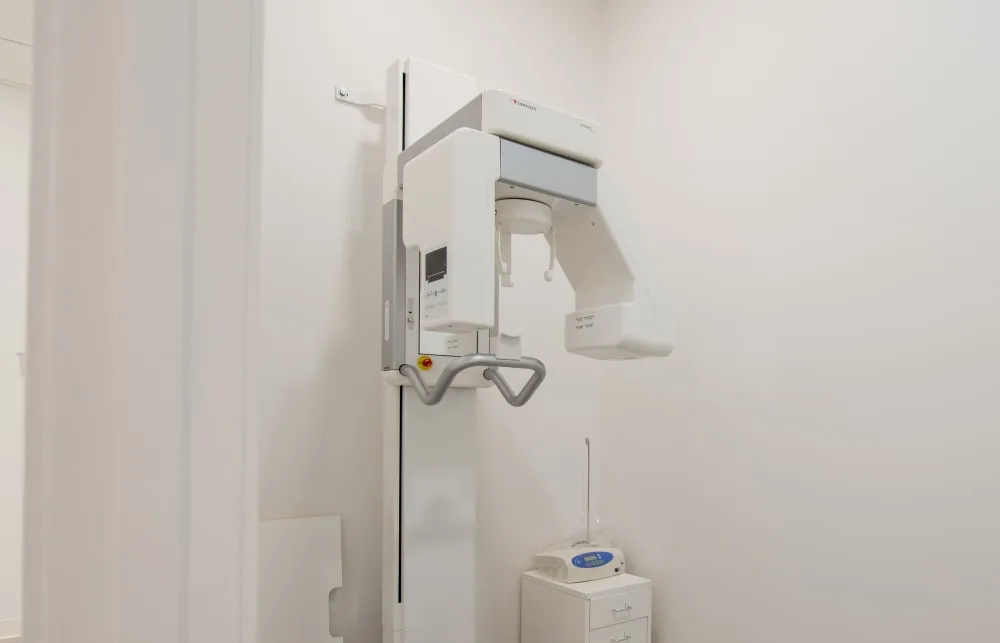 Dental X-ray machine in a bright examination room.