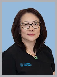 Professional portrait of a female dentist in scrubs.