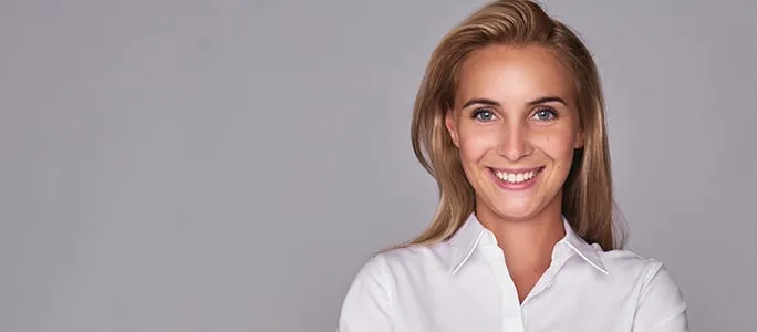 A smiling woman in a white shirt against a gray background.