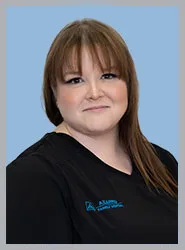 A dental professional smiling in a black uniform.