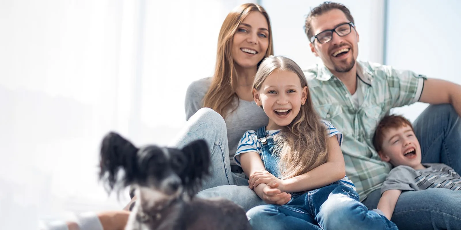 A happy family with two kids and a dog at home.