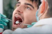 A dentist examining a patient's teeth in a clinic.