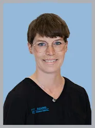 Smiling dental professional in a black uniform.