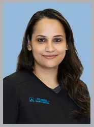 A dental professional in a black uniform against a blue background.