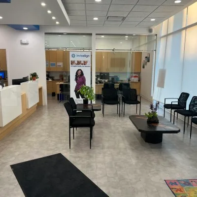 Bright dental clinic reception area with seating and an Invisalign banner.