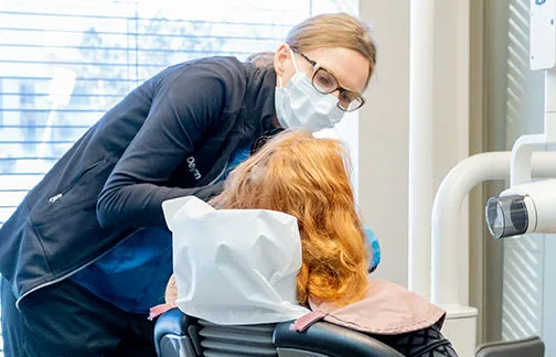 A dental hygienist assisting a patient in a clinic setting.