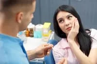 A dentist consulting with a young woman experiencing discomfort.