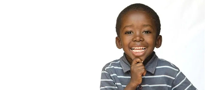 A cheerful boy smiling brightly against a plain background.