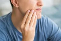 A young man showing signs of dental discomfort.