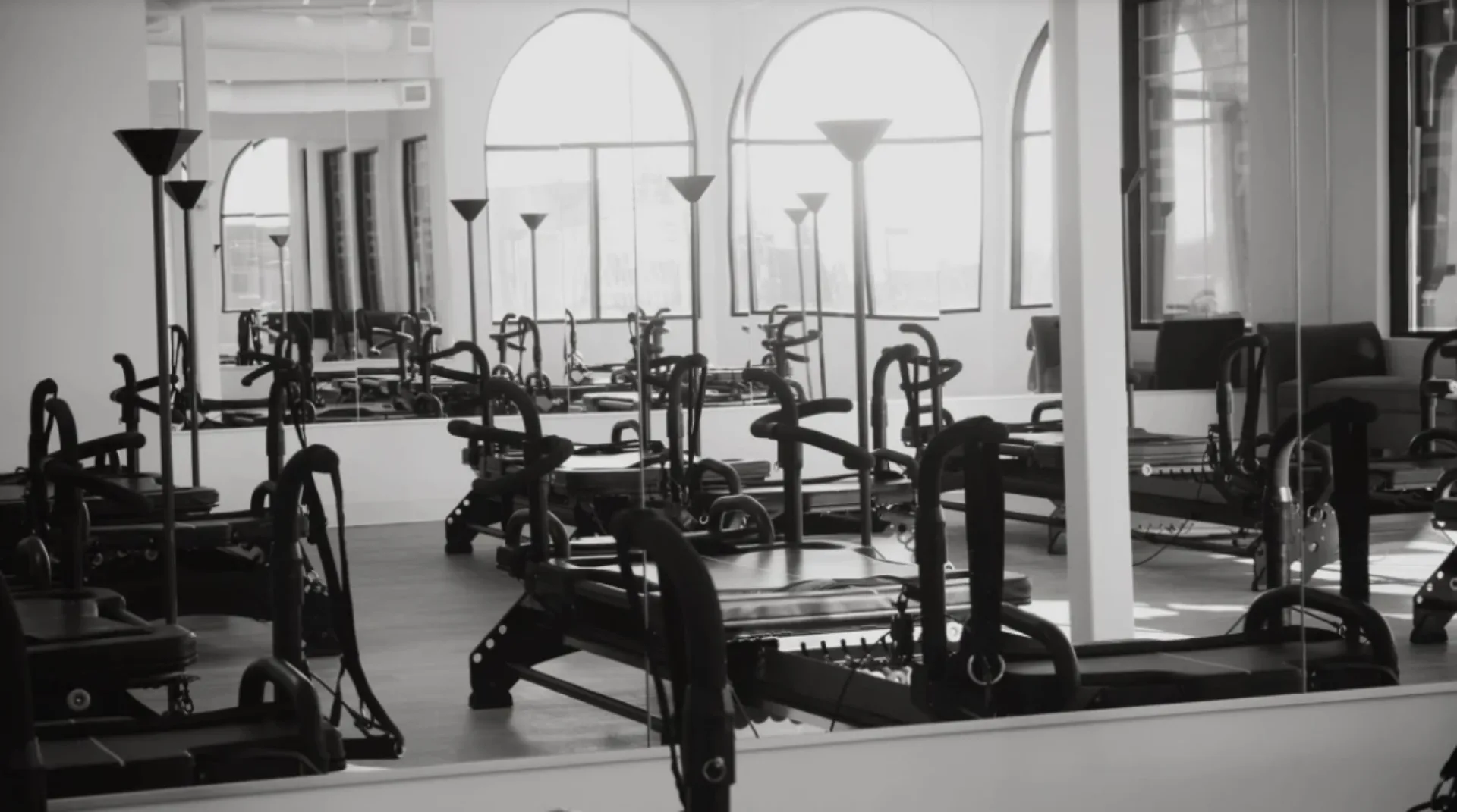 A fitness studio with exercise reformers and large windows.