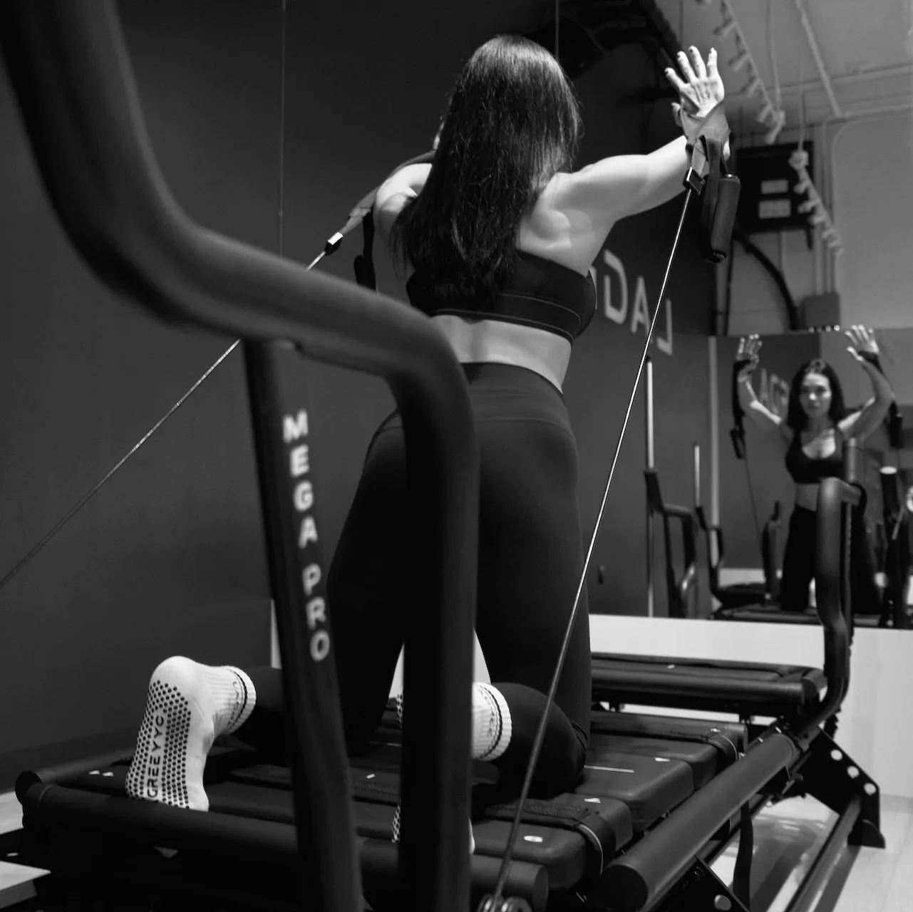 A woman using a Megaformer workout machine in a studio.