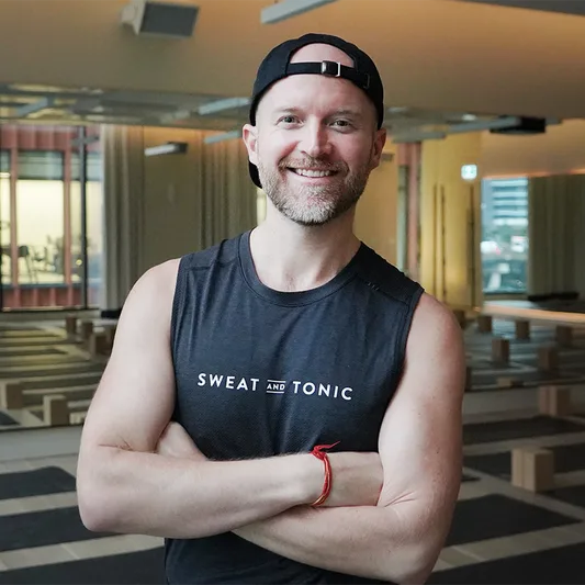 A fitness instructor in a yoga studio wearing a branded tank top.