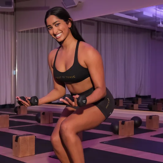 A fitness instructor demonstrating a strength exercise in a studio.
