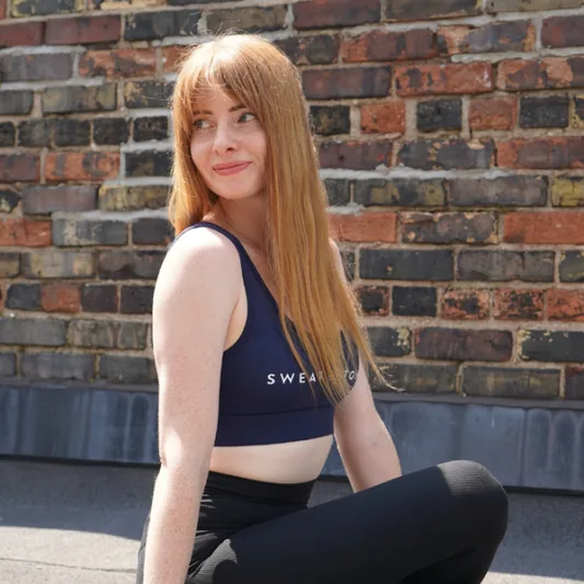 Woman with red hair sitting against a brick wall.