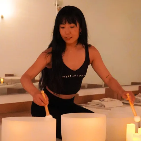A woman playing crystal singing bowls in a wellness studio.