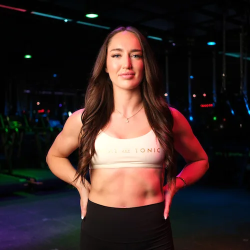 A woman in fitness wear posing confidently in a studio.