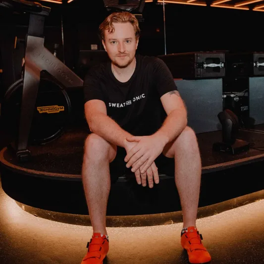 A man in athletic wear sitting in a fitness studio.