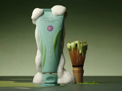 Tatcha Matcha Foam Cleanser and matcha whisk on a surface.