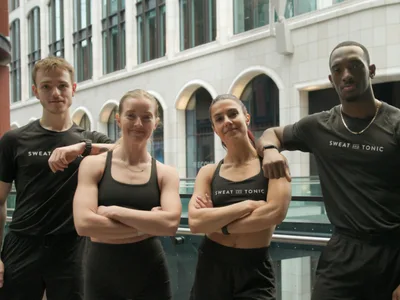 Four fitness instructors in black workout gear posing together.