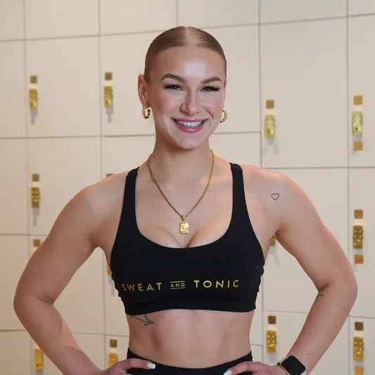Fitness instructor smiling in front of lockers.