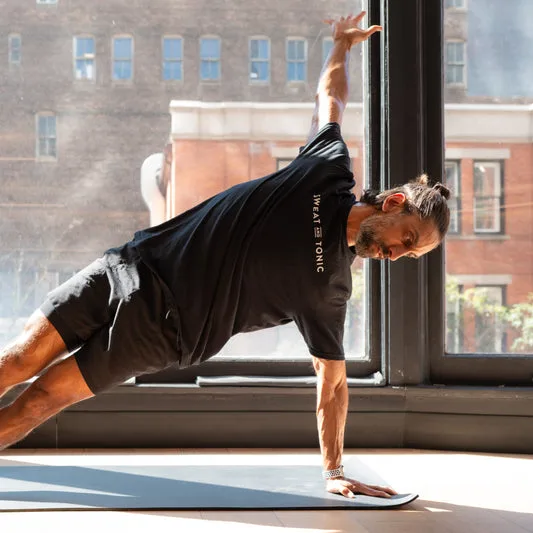 A male instructor doing a side plank in a fitness studio.