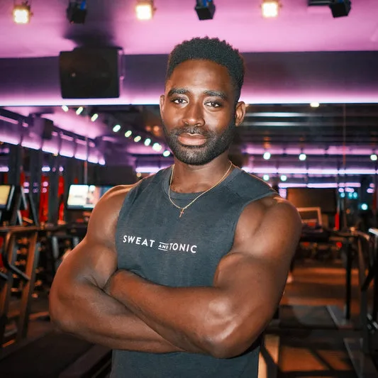 A man posing in a fitness studio with gym equipment.