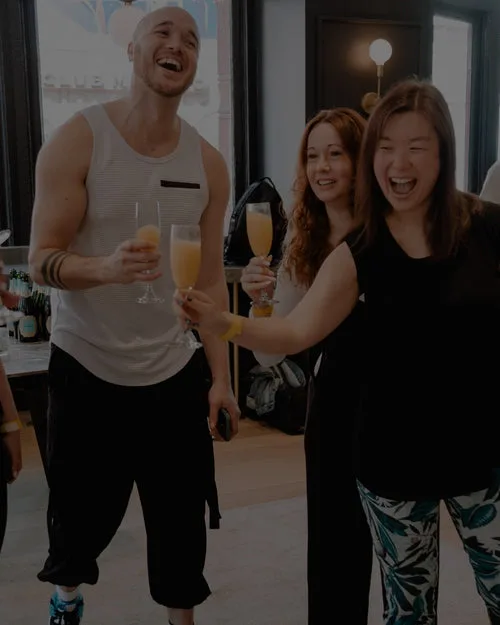 Three people celebrating with glasses of mimosa indoors.