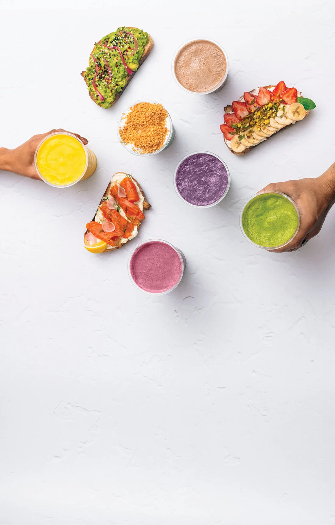 An assortment of smoothies and healthy snacks on a white surface.