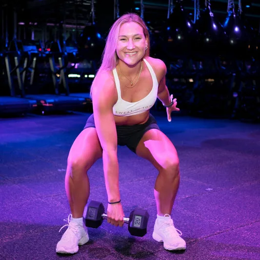 A woman exercising with a dumbbell in a gym.