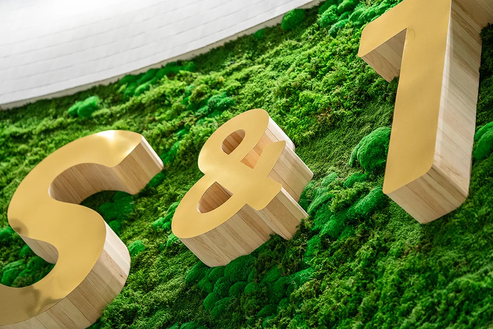 Stylized gold monogram on a moss background.