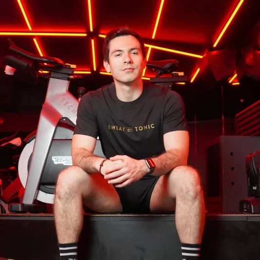 A man in a fitness studio wearing a Sweat and Tonic t-shirt.
